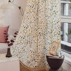 a white curtain with yellow flowers hanging from it's side in front of a window