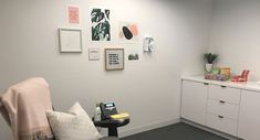 an office with white walls and grey carpeting, some pictures on the wall behind a chair