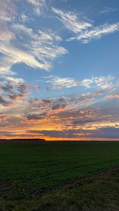 the sun is setting over an open field