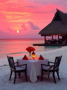 a dinner table set up on the beach at sunset