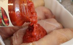 a person pouring sauce onto some meat in a white container