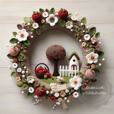 a knitted wreath with an apple tree, birdhouse and flowers