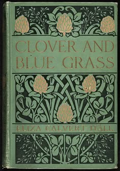 an old book with flowers and blue grass written in gold on the front cover, sitting on a black surface