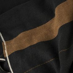 the back of a black and brown blanket with white stitching on it's edges