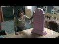 a woman standing next to a large pink object on top of a wooden table in a room