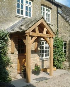 an outside view of a stone building with a wooden pergolated structure and white windows