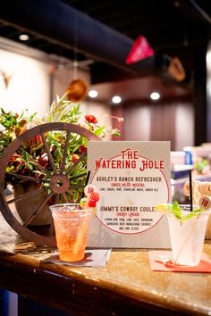 a table topped with drinks next to a sign that says the watering jolie on it