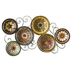 five decorative plates are hanging on a wall with wrought iron brackets and flowers painted on them