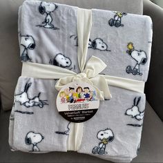 a blanket wrapped in white with snoopy characters on it and a tag that says, peanuts