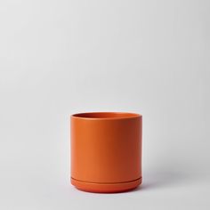 an orange cup sitting on top of a white table