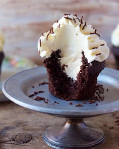 a chocolate cupcake with white frosting and sprinkles on a plate