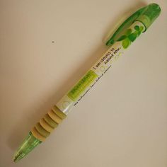 a green and yellow toothbrush sitting on top of a white table next to a tube