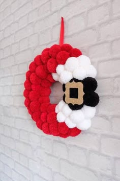 a red and white christmas wreath hanging on a brick wall next to a black and white santa clause ornament