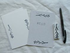 two cards with the word hello written on them next to a pen and ink roller