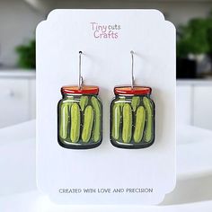 a pair of earrings with pickles hanging from it's hooks on a card