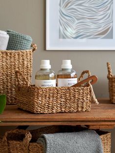 three bottles of hand sanitizers sit in baskets on a table next to towels