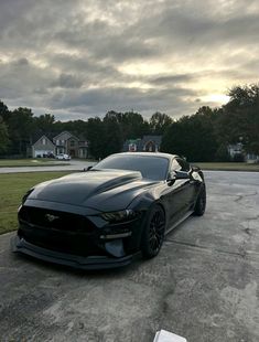 a black mustang parked on top of a parking lot