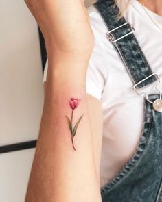 a woman's arm with a small flower tattoo on the left side of her arm