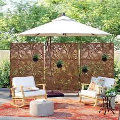 an outdoor area with chairs, umbrella and rug on the ground in front of trees