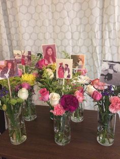 several vases with flowers and pictures in them on a table next to a curtain