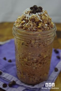 a glass jar filled with granola on top of a blue napkin and chocolate chips