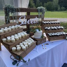 a table topped with lots of cupcakes next to a wooden sign that says sweet