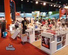 a group of people standing around a booth at a book fair with books on display