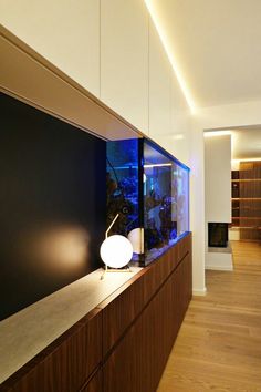 a fish tank sitting on top of a wooden shelf next to a wall mounted aquarium