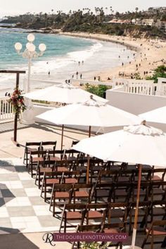 tables and umbrellas set up on the beach for an outdoor wedding ceremony with ocean in background