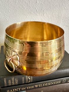 a brass bowl sitting on top of two books