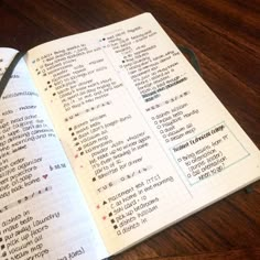 an open notebook with some writing in it on a wooden table next to a pair of scissors