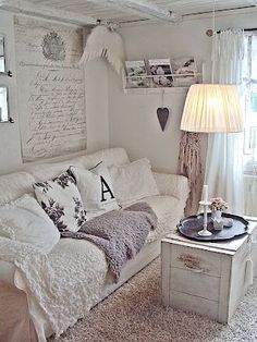 a living room filled with white furniture and lots of pillows on top of the couch