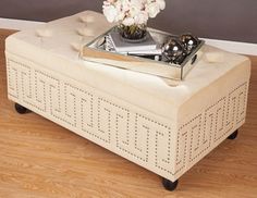 a white ottoman sitting on top of a wooden floor next to a vase with flowers