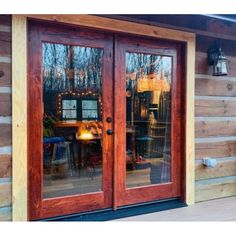 the front door of a log cabin with two glass doors and lights on each side