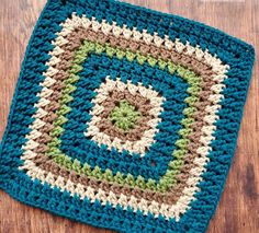 a crocheted square on a wooden surface