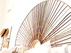 a large bamboo fan sitting on top of a bed next to pillows and pillow cases