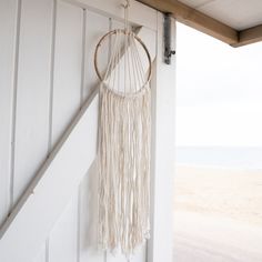 a white wall hanging on the side of a building next to an open door and beach