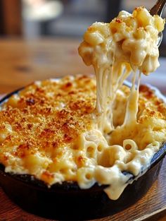 a fork is lifting up macaroni and cheese from a dish on a plate