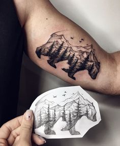 a man's arm with mountains and trees tattoo on the left side of his arm