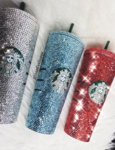 three glitter starbucks tumblers are sitting next to each other