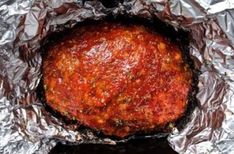 a meatball covered in marinara sauce on top of aluminum foil