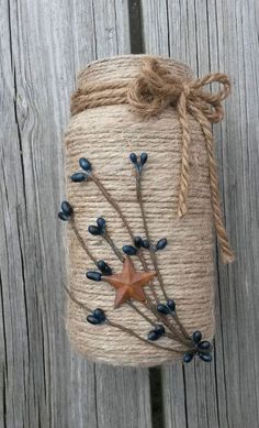 a mason jar decorated with blue berries and twine is hanging on a wooden fence