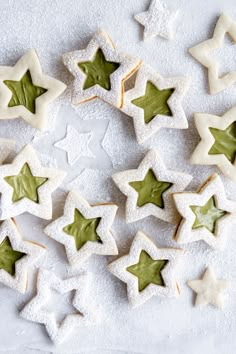 star shaped cookies with green icing on a white tablecloth covered in powdered sugar