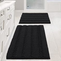 two black rugs on the floor in a bathroom