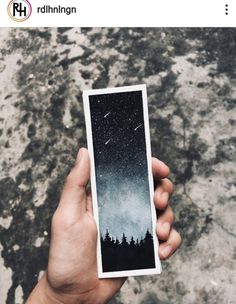 someone holding up a polaroid with the sky in the background and trees on it