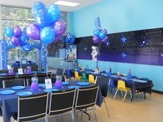 a room filled with tables and chairs covered in blue and purple balloons, plates and napkins