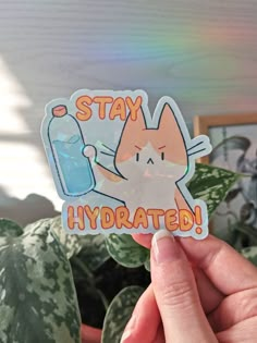 someone holding up a sticker that says stay hydrated in front of a houseplant