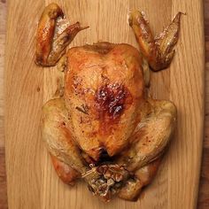 a whole chicken sitting on top of a wooden cutting board