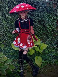 a woman wearing a red and white polka dot dress, black tights, knee high boots and an umbrella over her head