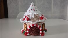 a small crocheted house on top of a white table next to a tile wall